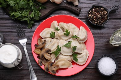 Delicious dumplings (varenyky) with potatoes, mushrooms and parsley served on brown wooden table, flat lay