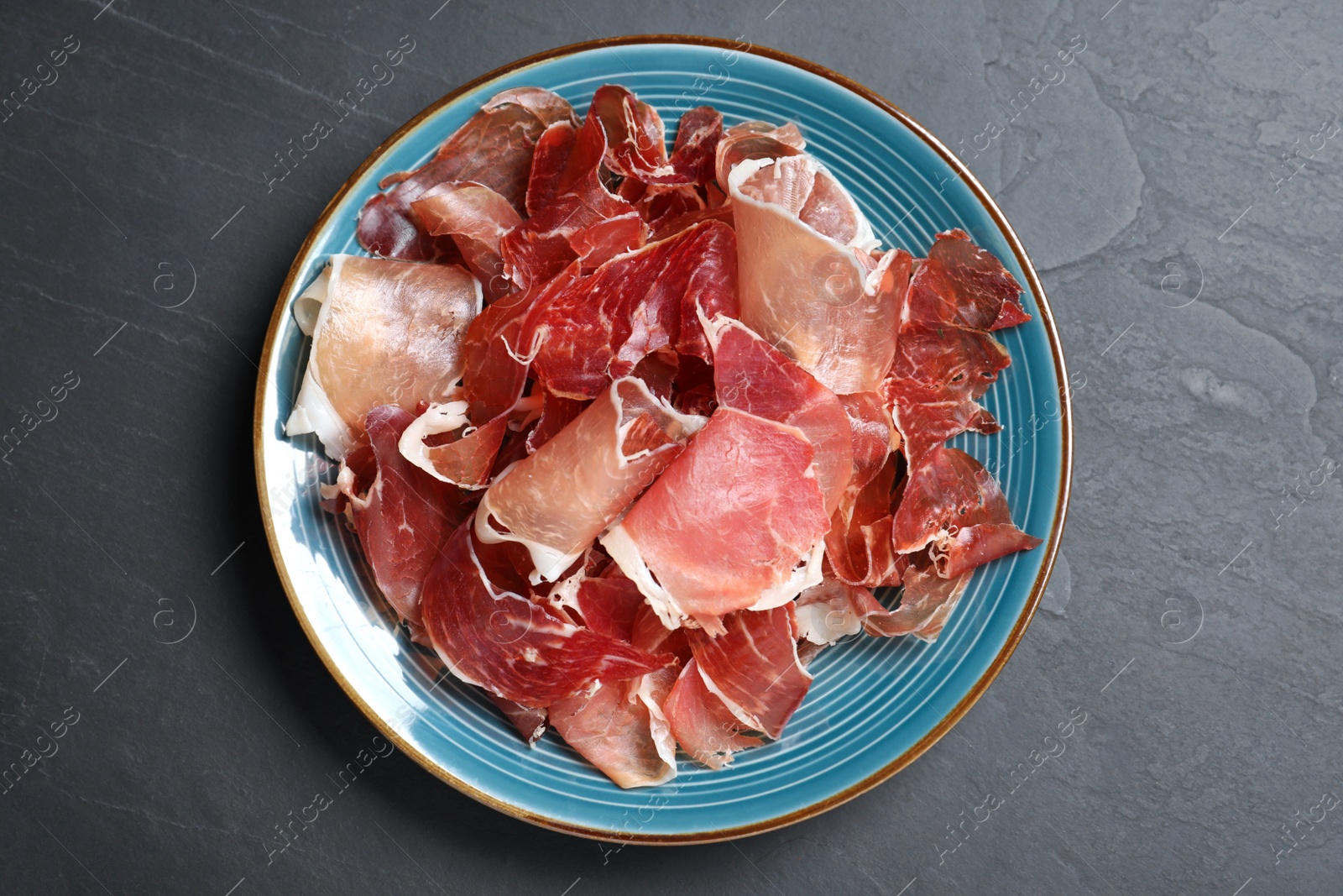 Photo of Tasty prosciutto on black table, top view