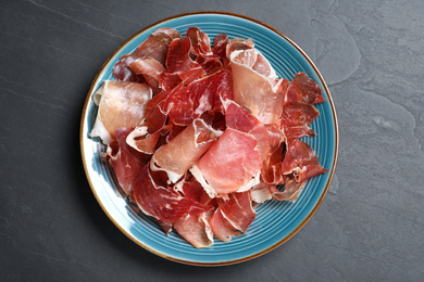 Photo of Tasty prosciutto on black table, top view