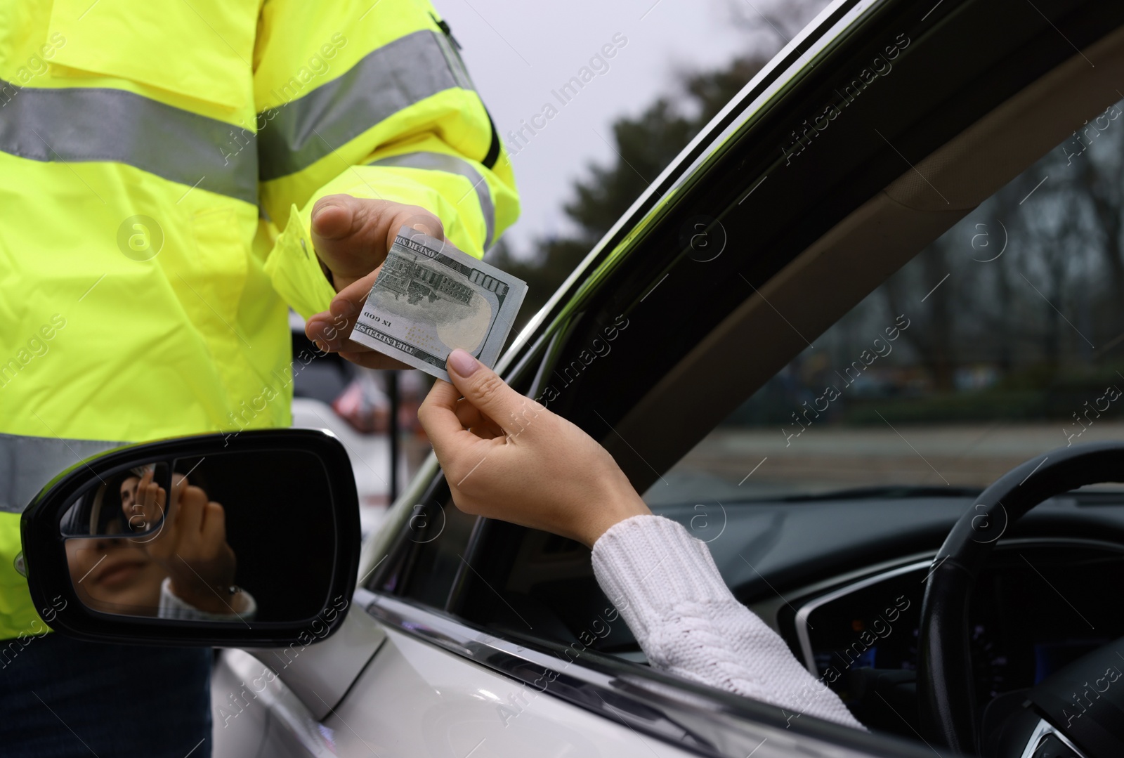 Photo of Woman giving bribe to police officer out of car window, closeup