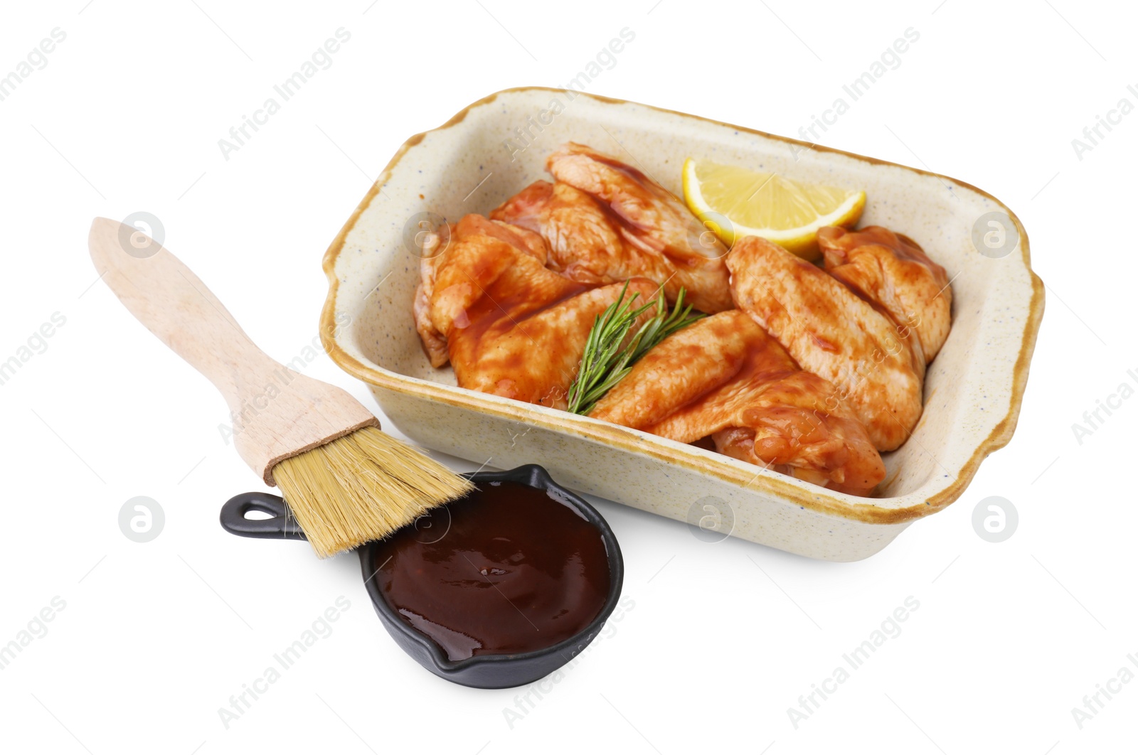 Photo of Fresh marinade, basting brush, raw chicken wings, rosemary and lemon isolated on white