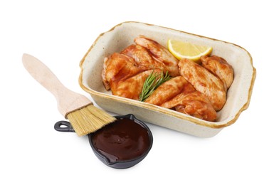 Photo of Fresh marinade, basting brush, raw chicken wings, rosemary and lemon isolated on white