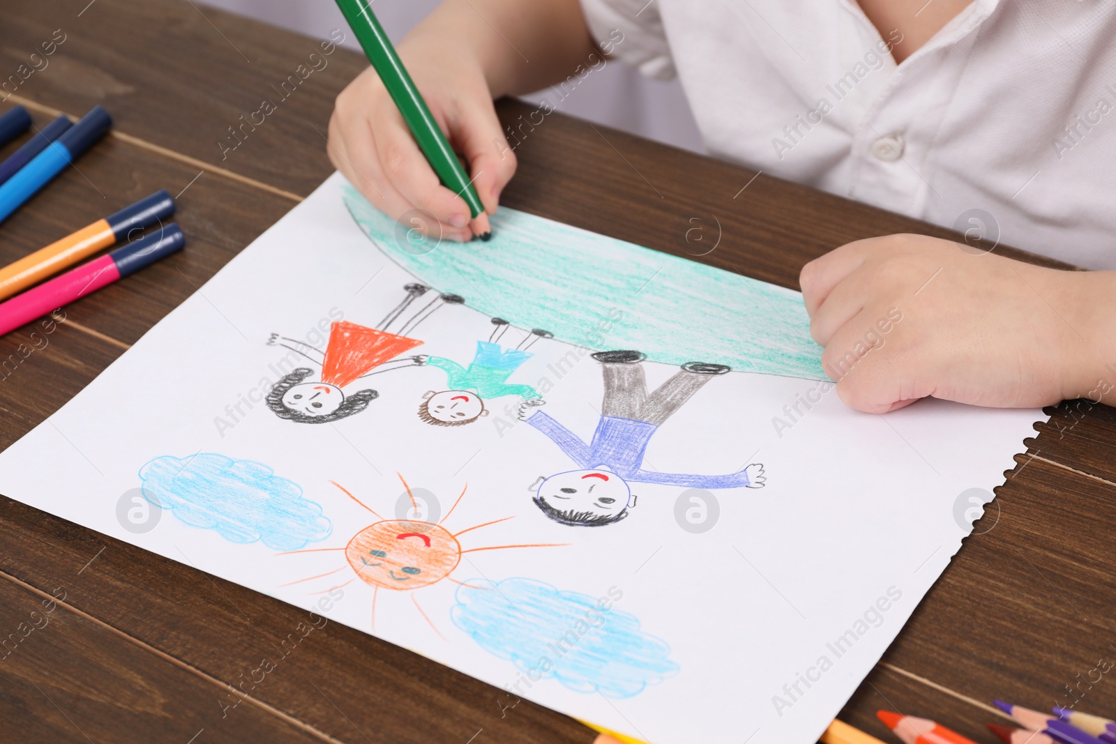 Photo of Little boy drawing with pencil at wooden table, closeup. Child`s art