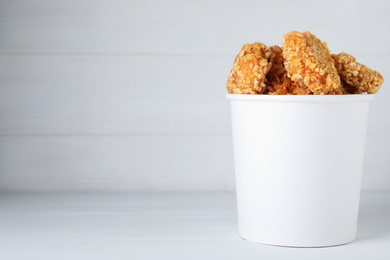 Photo of Bucket with yummy nuggets on wooden table, space for text
