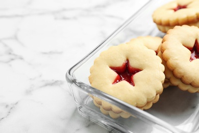 Photo of Traditional Christmas Linzer cookies with sweet jam in glass dish on marble background