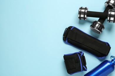 Photo of Weighting agents, dumbbells and sport bottle on light blue background, flat lay. Space for text