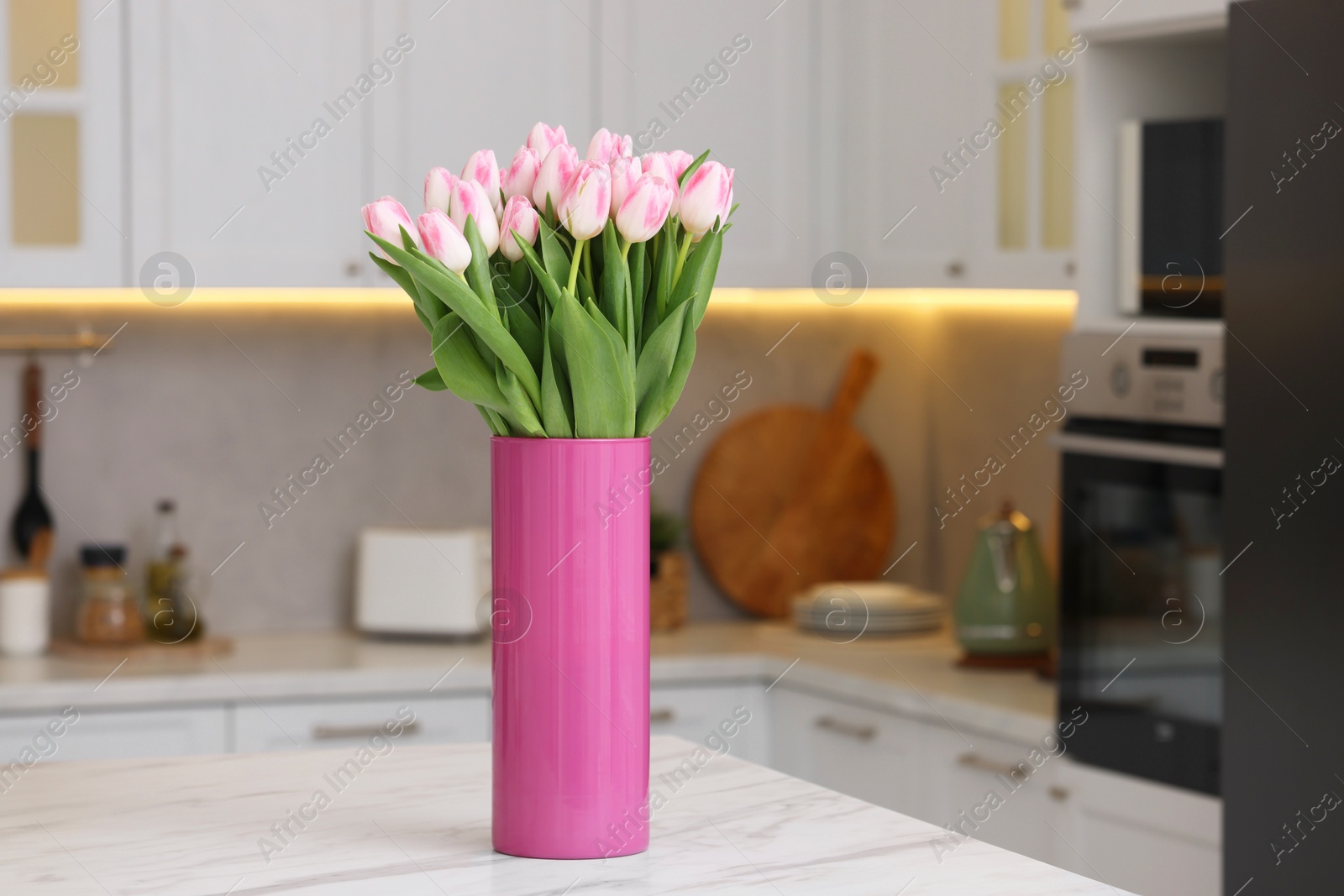 Photo of Beautiful bouquet of fresh pink tulips on table in kitchen