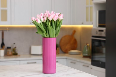 Beautiful bouquet of fresh pink tulips on table in kitchen