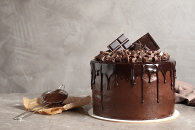 Photo of Freshly made delicious chocolate cake on marble table against grey background. Space for text