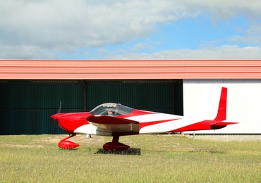 Photo of Ultralight airplane on green grass near hangar
