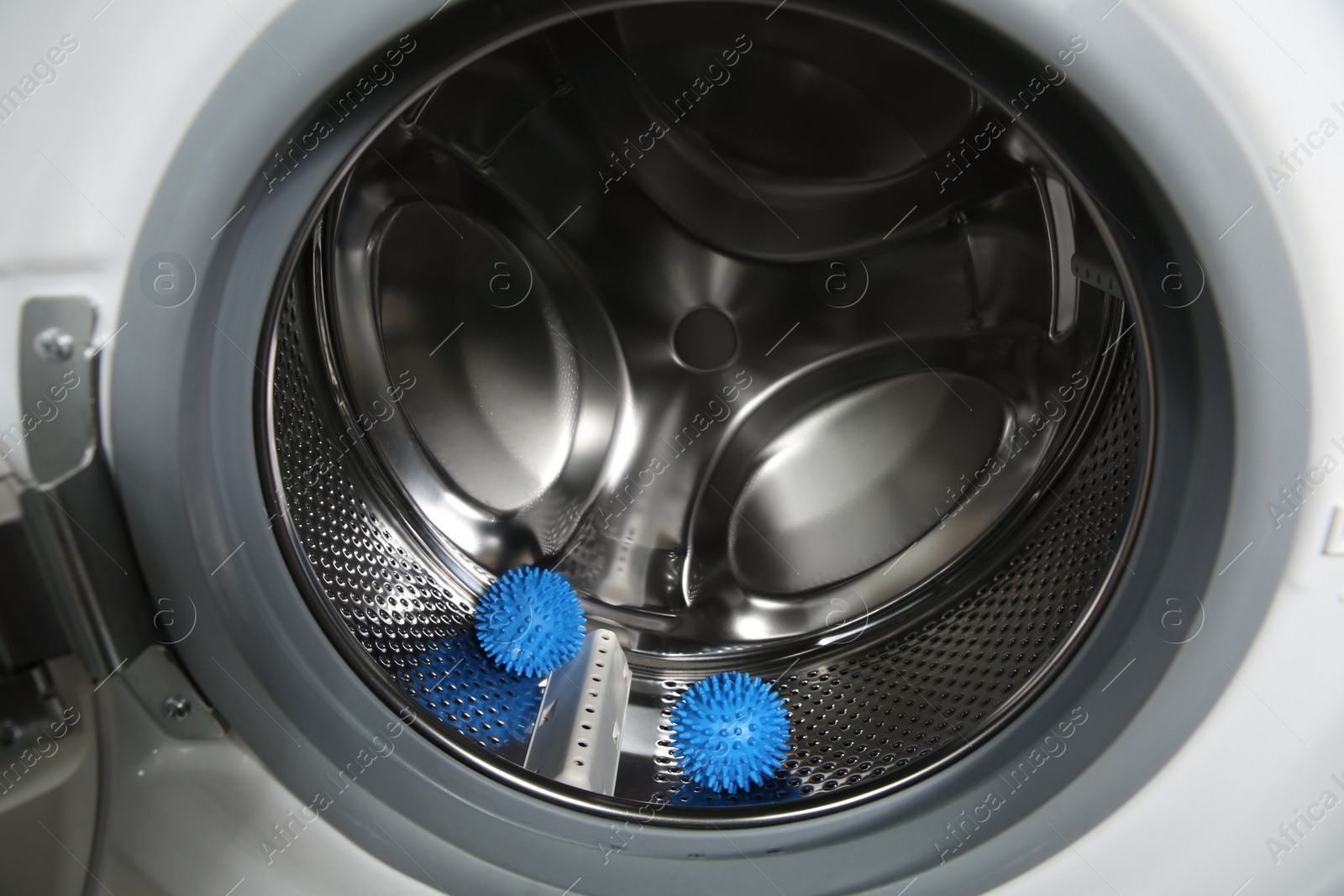 Photo of Blue dryer balls in washing machine drum, closeup