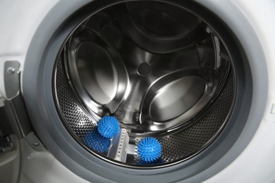 Photo of Blue dryer balls in washing machine drum, closeup