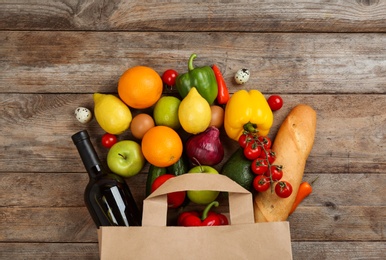 Photo of Flat lay composition with overturned paper bag and groceries on wooden table