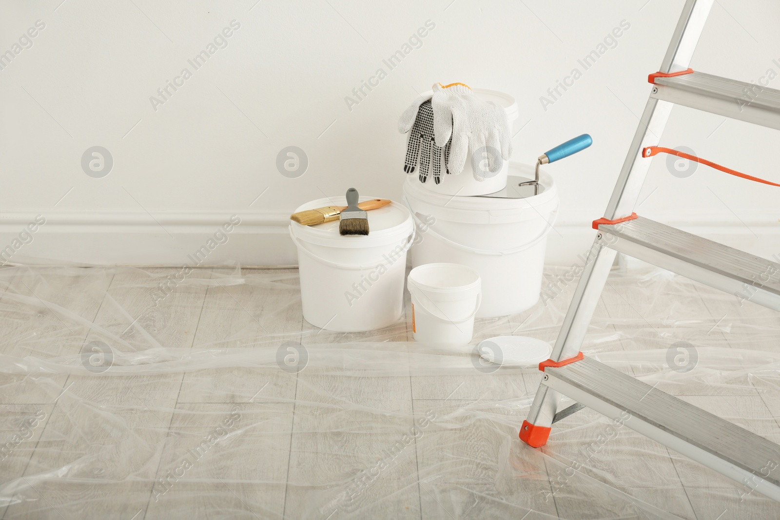 Photo of Stepladder and different tools near wall in room. Interior renovation