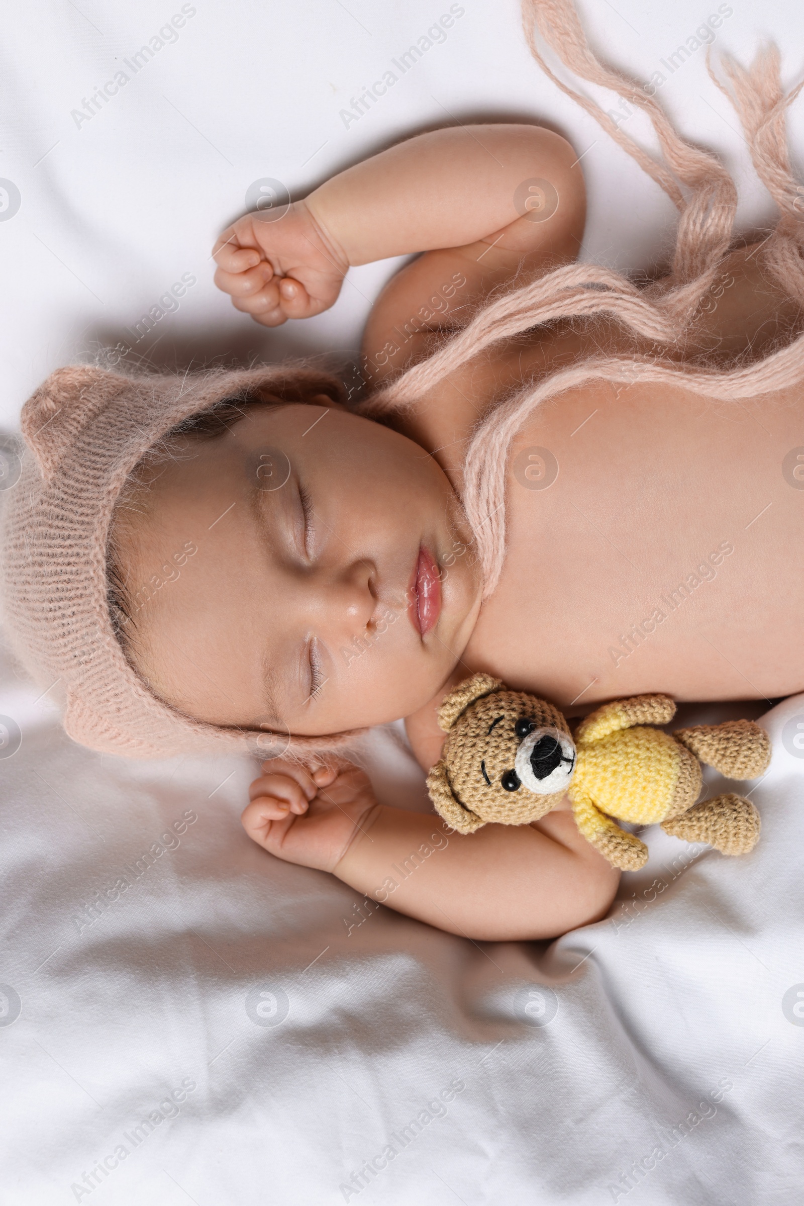 Photo of Cute little baby with toy bear sleeping on soft bed, top view