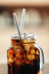 Mason jar of cola with ice against blurred background