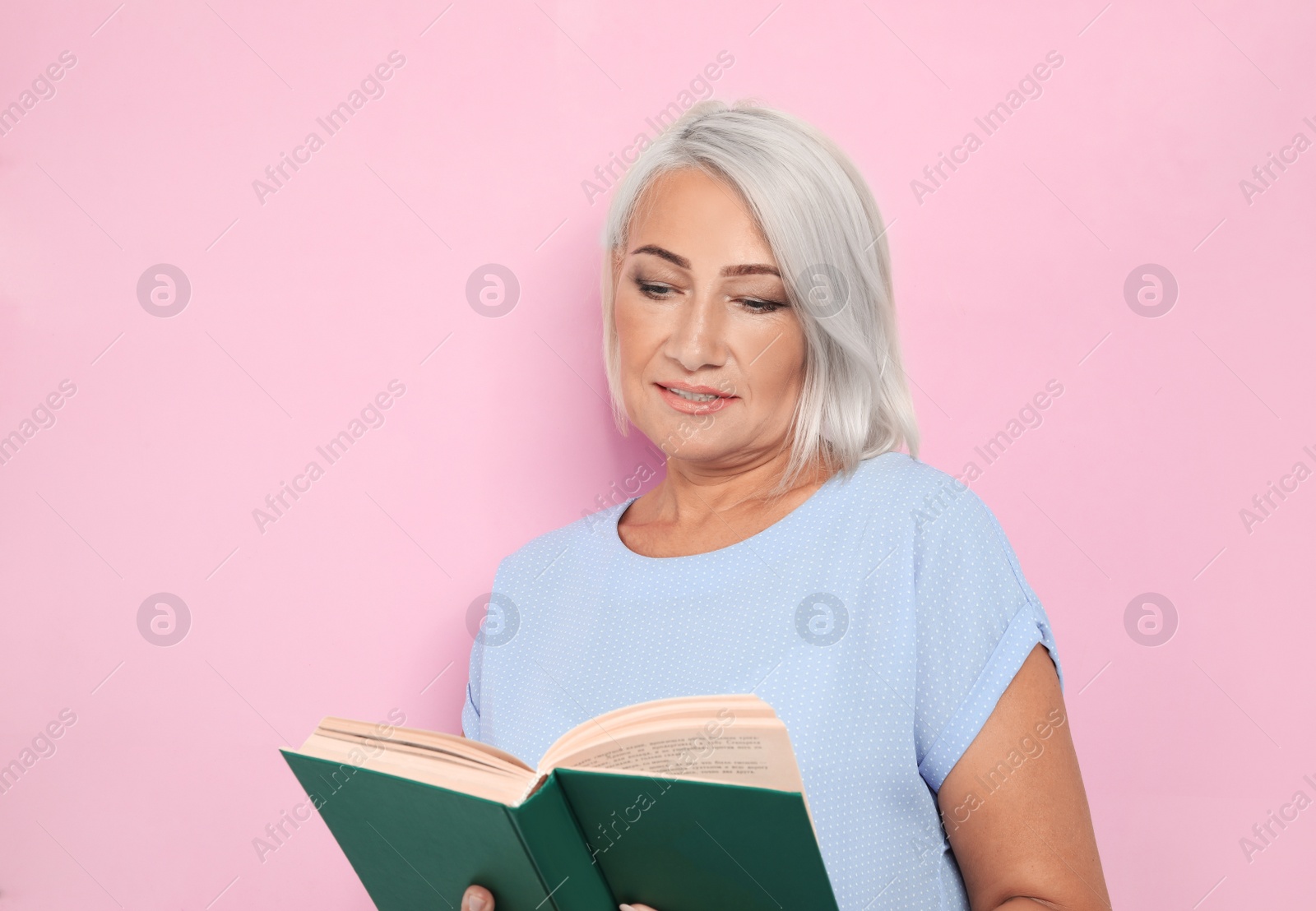 Photo of Mature woman reading book on pink background