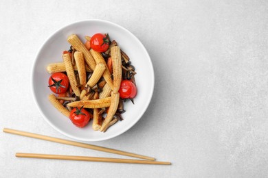 Tasty roasted baby corn with tomatoes, mushrooms and chopsticks on light grey table, flat lay. Space for text