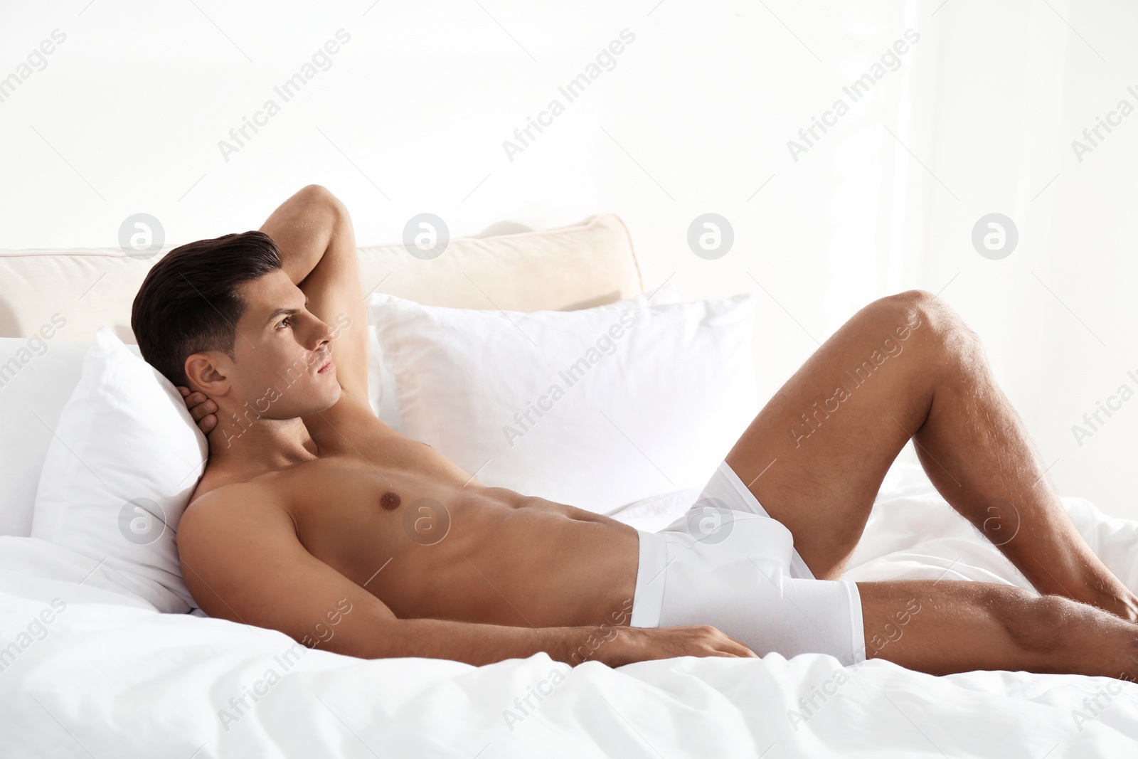 Photo of Handsome man in white underwear on bed indoors