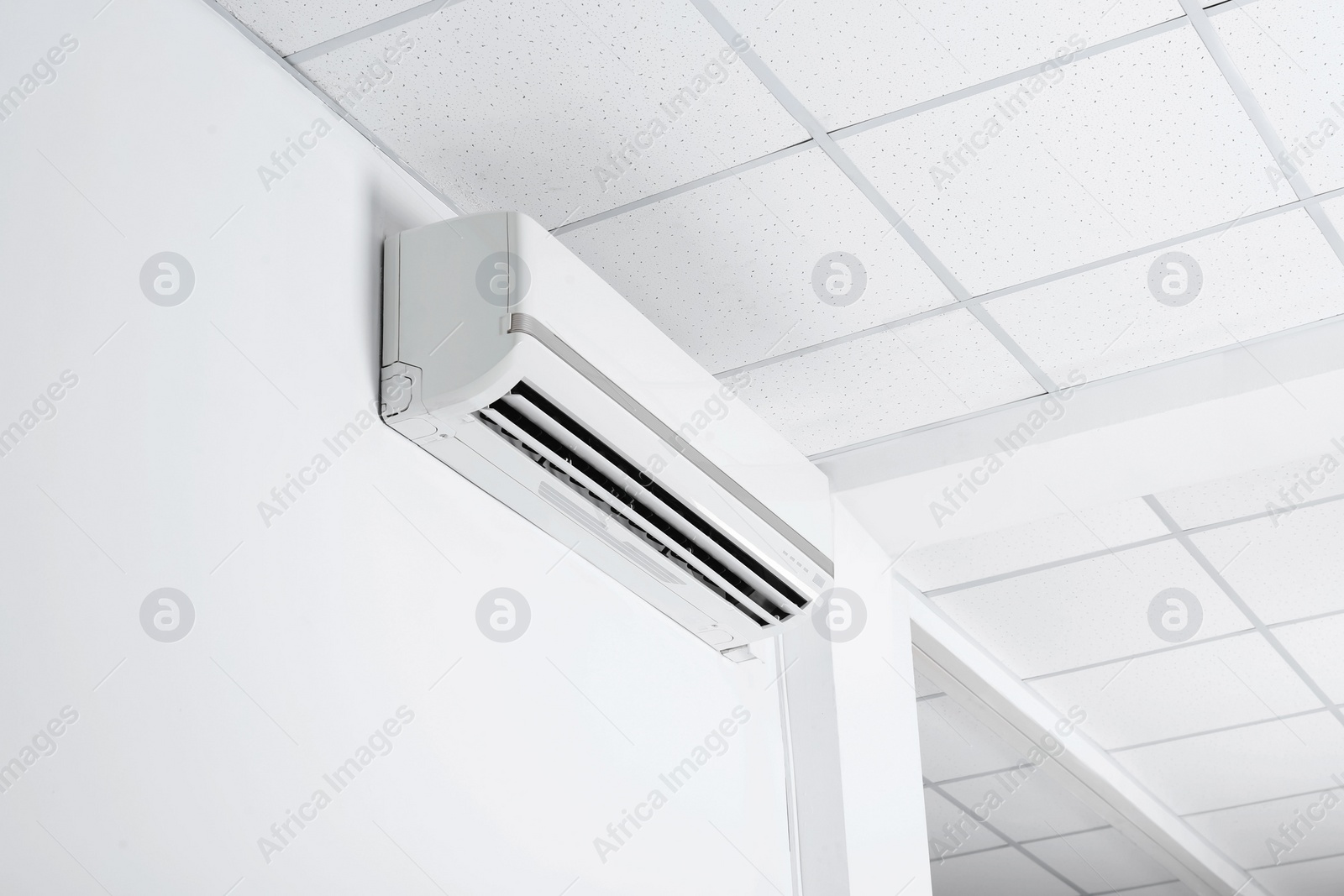 Photo of Modern air conditioner on white wall indoors, low angle view