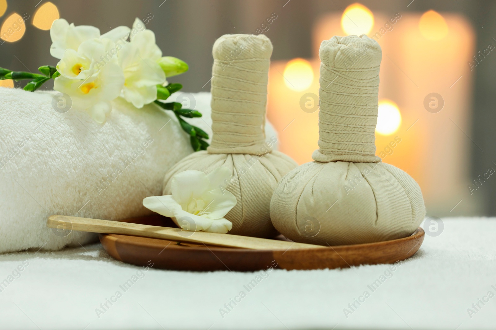 Photo of Beautiful composition with different spa products and flowers on white towel against blurred background, closeup