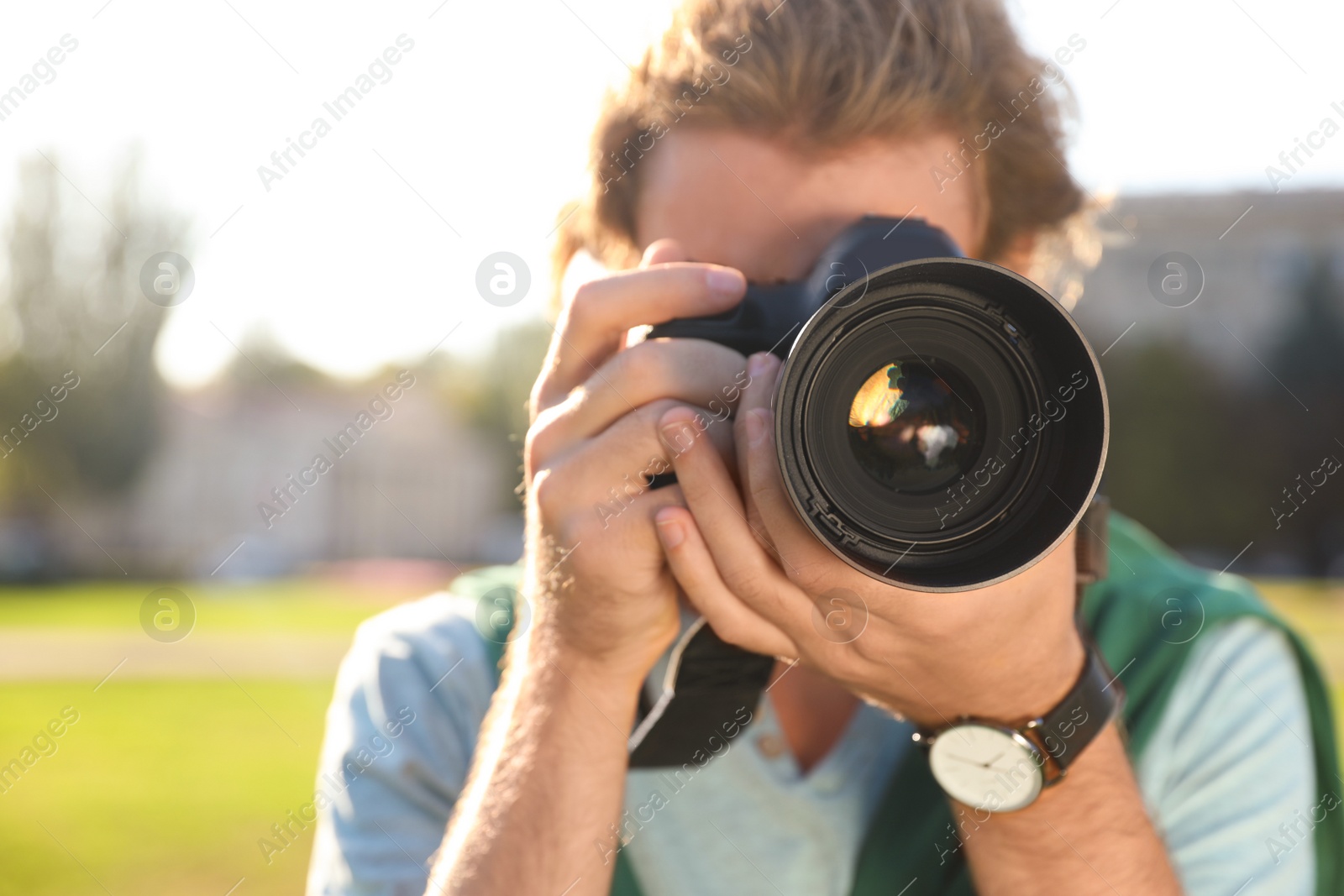 Photo of Young male photographer taking photo with professional camera on street, closeup