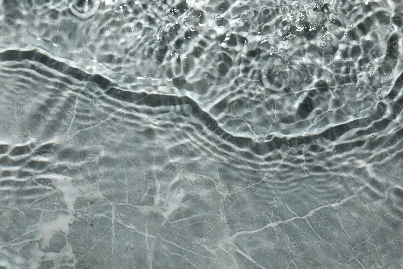 Photo of Rippled surface of clear water on light grey textured background, top view