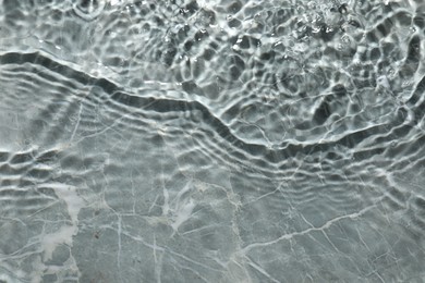 Photo of Rippled surface of clear water on light grey textured background, top view