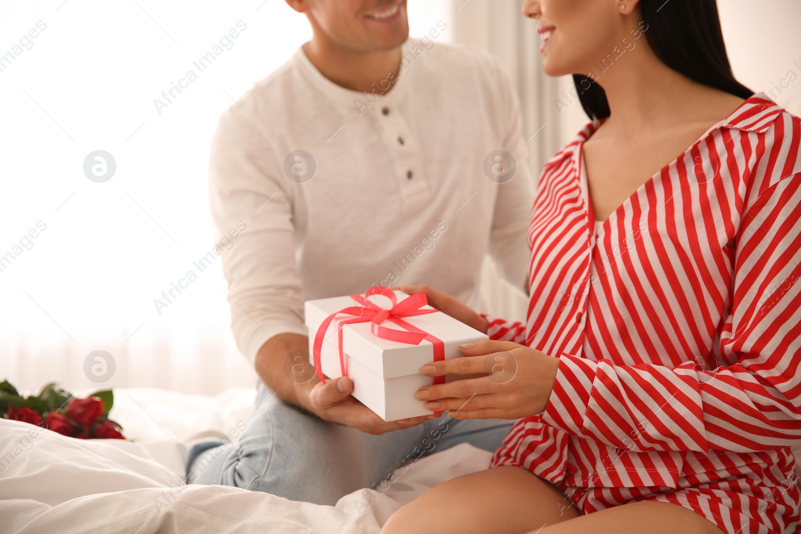 Photo of Lovely couple with gift box at home, closeup. Valentine's day celebration