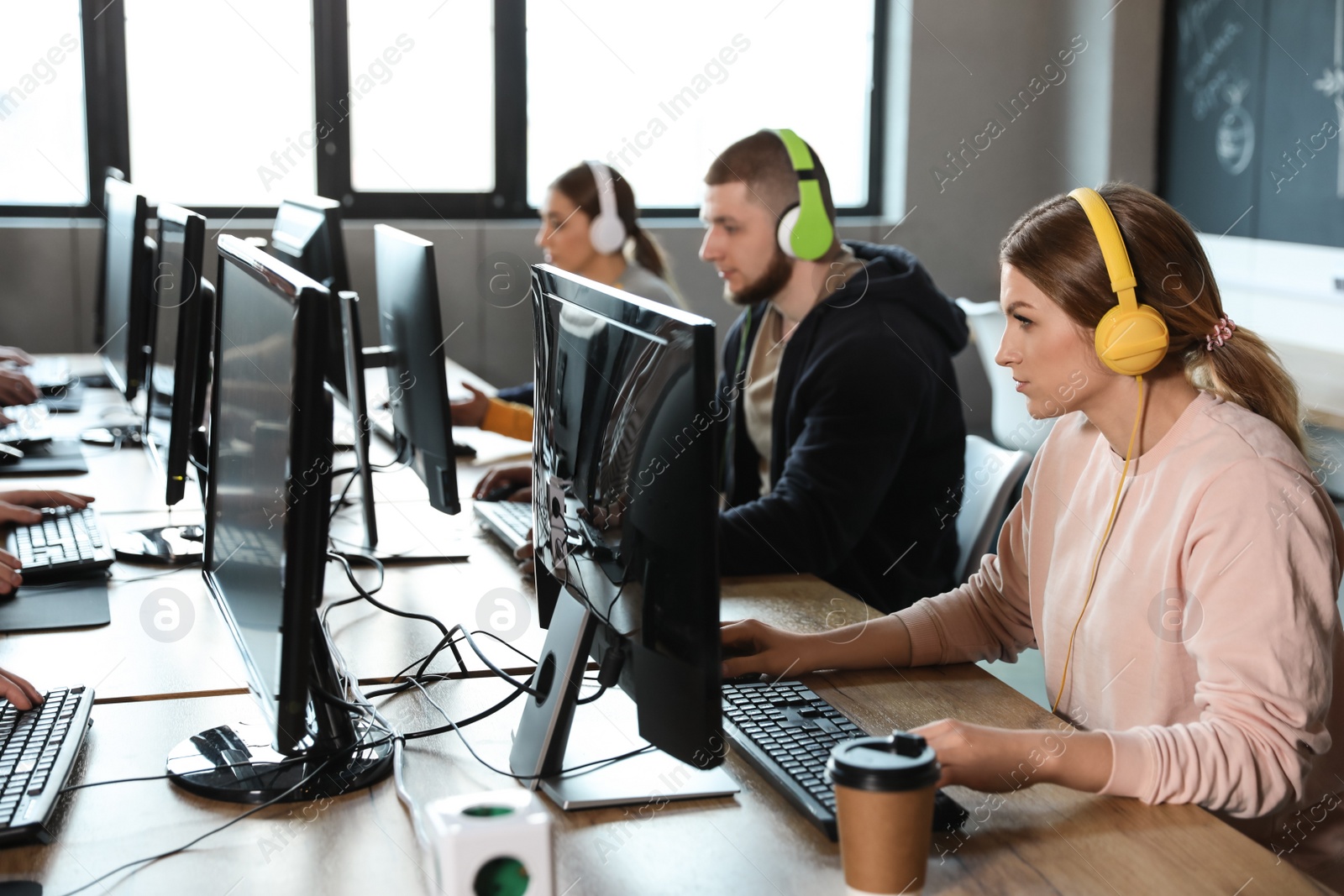 Photo of Group of people playing video games in internet cafe