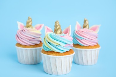 Photo of Cute sweet unicorn cupcakes on light blue background