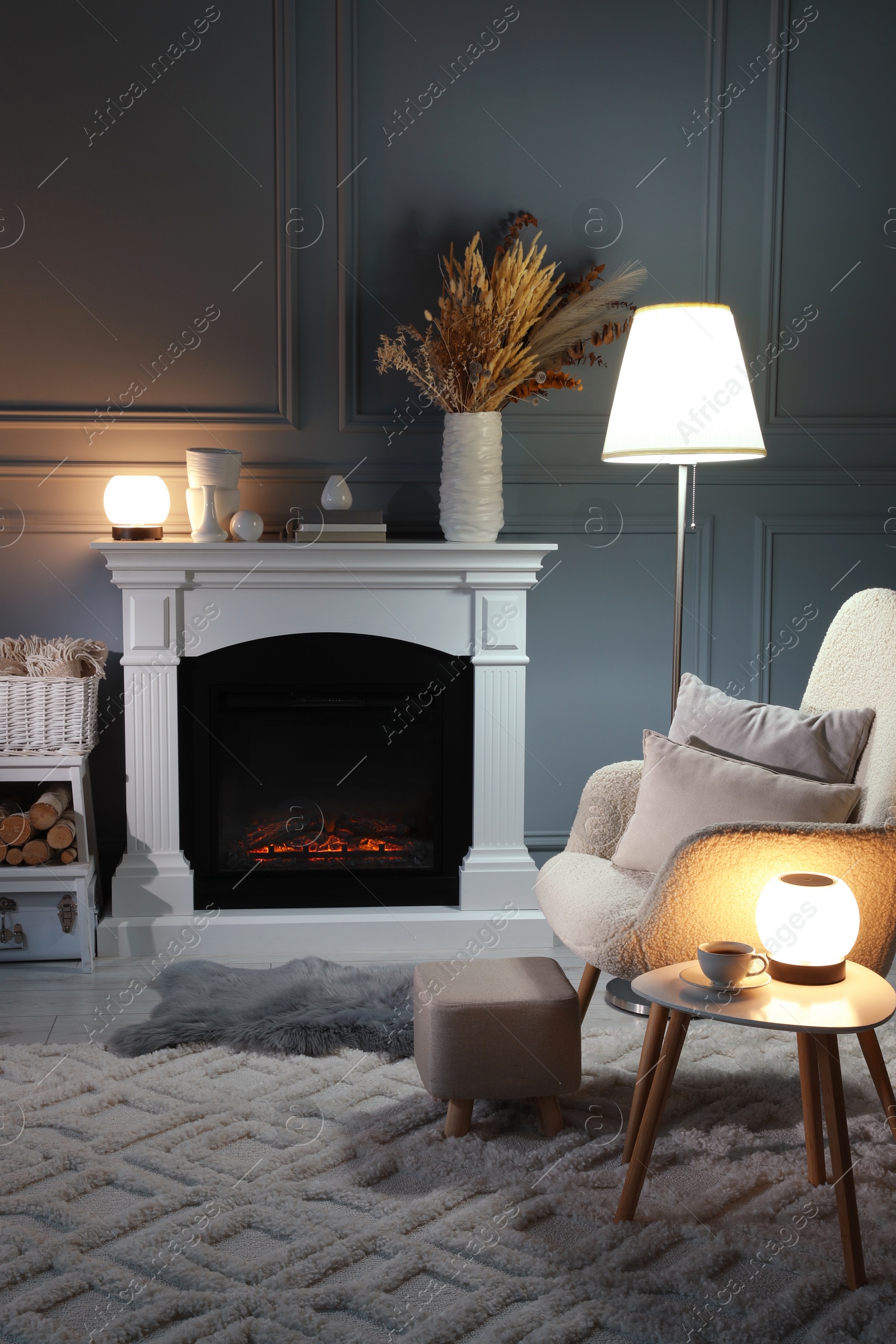 Photo of Beautiful fireplace, different decor and armchair in living room. Interior design