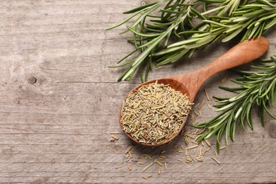Photo of Spoon with dry and fresh rosemary on wooden table, flat lay. Space for text
