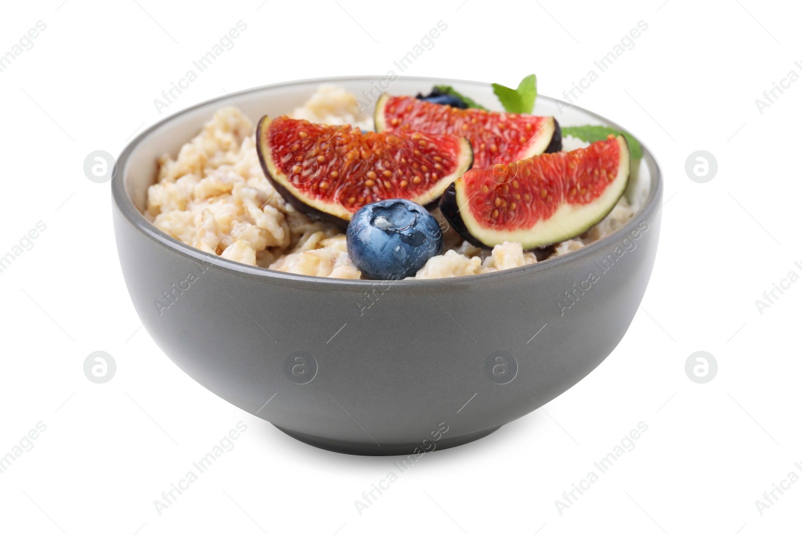 Photo of Bowl of oatmeal with blueberries, mint and fig pieces isolated on white