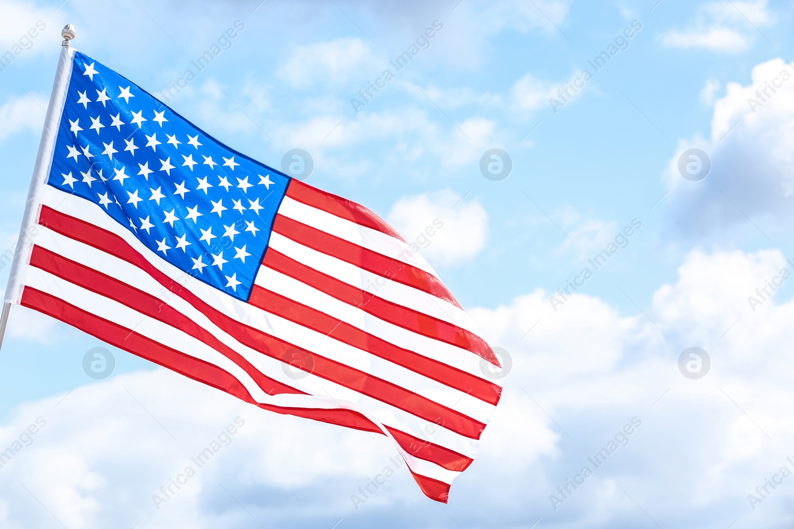 Photo of American flag outdoors on cloudy day. Space for text