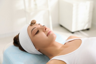 Photo of Young woman receiving snail facial massage in spa salon