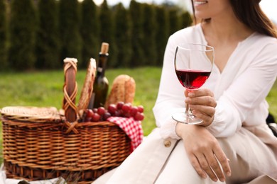 Photo of Woman with glass of wine having picnic in park, closeup