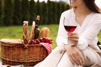 Woman with glass of wine having picnic in park, closeup