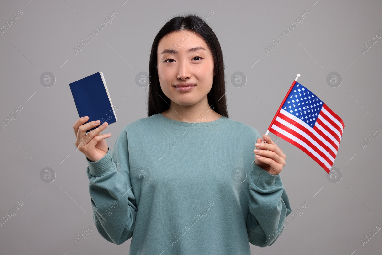 Photo of Immigration to United States of America. Woman with passport and flag on grey background