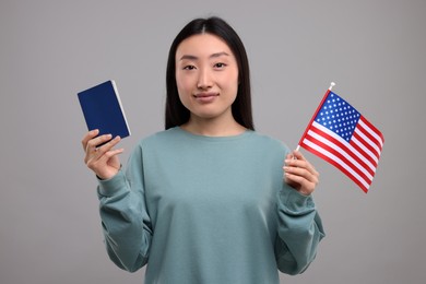 Immigration to United States of America. Woman with passport and flag on grey background