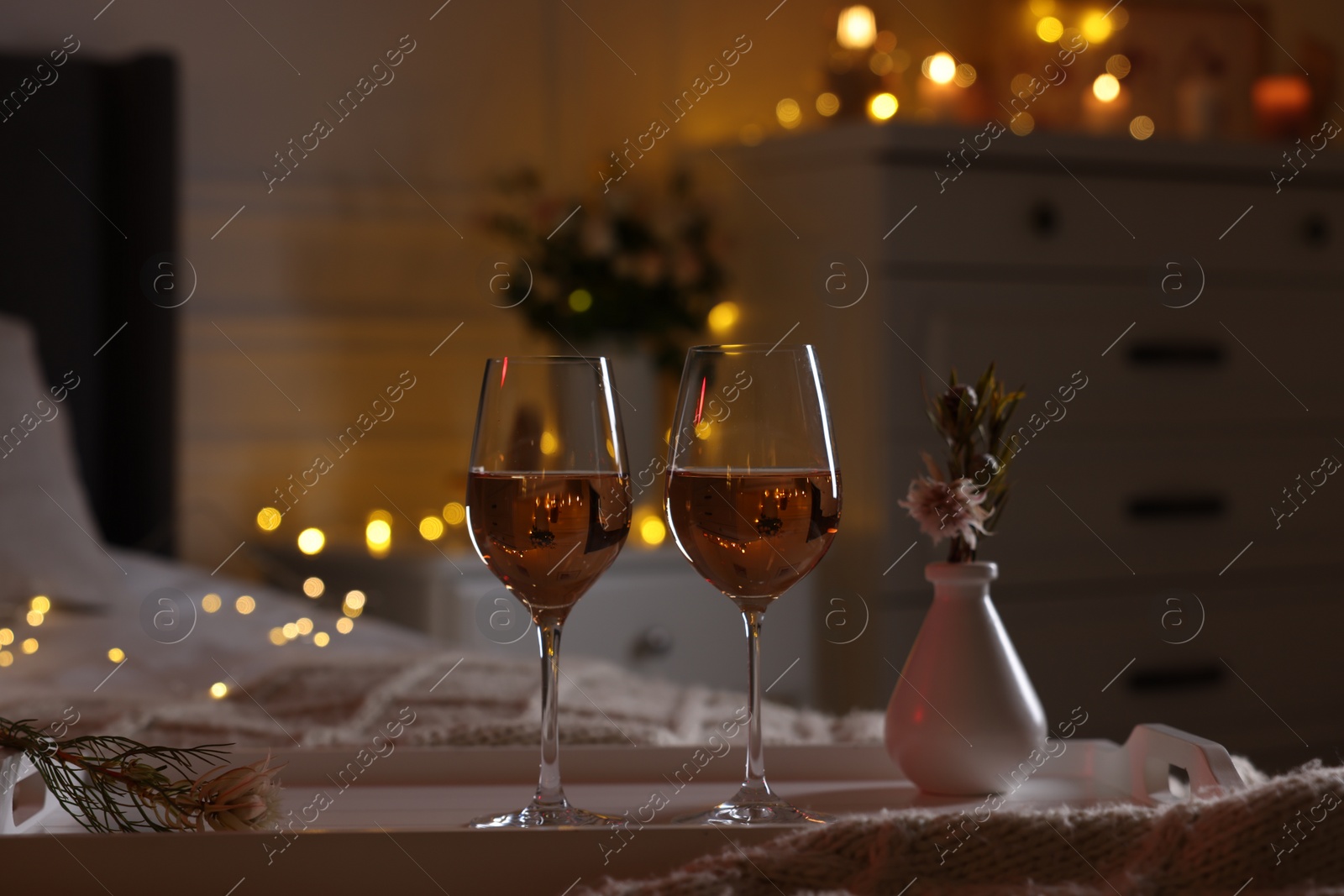 Photo of Glasses of wine in bedroom adorned for romantic evening