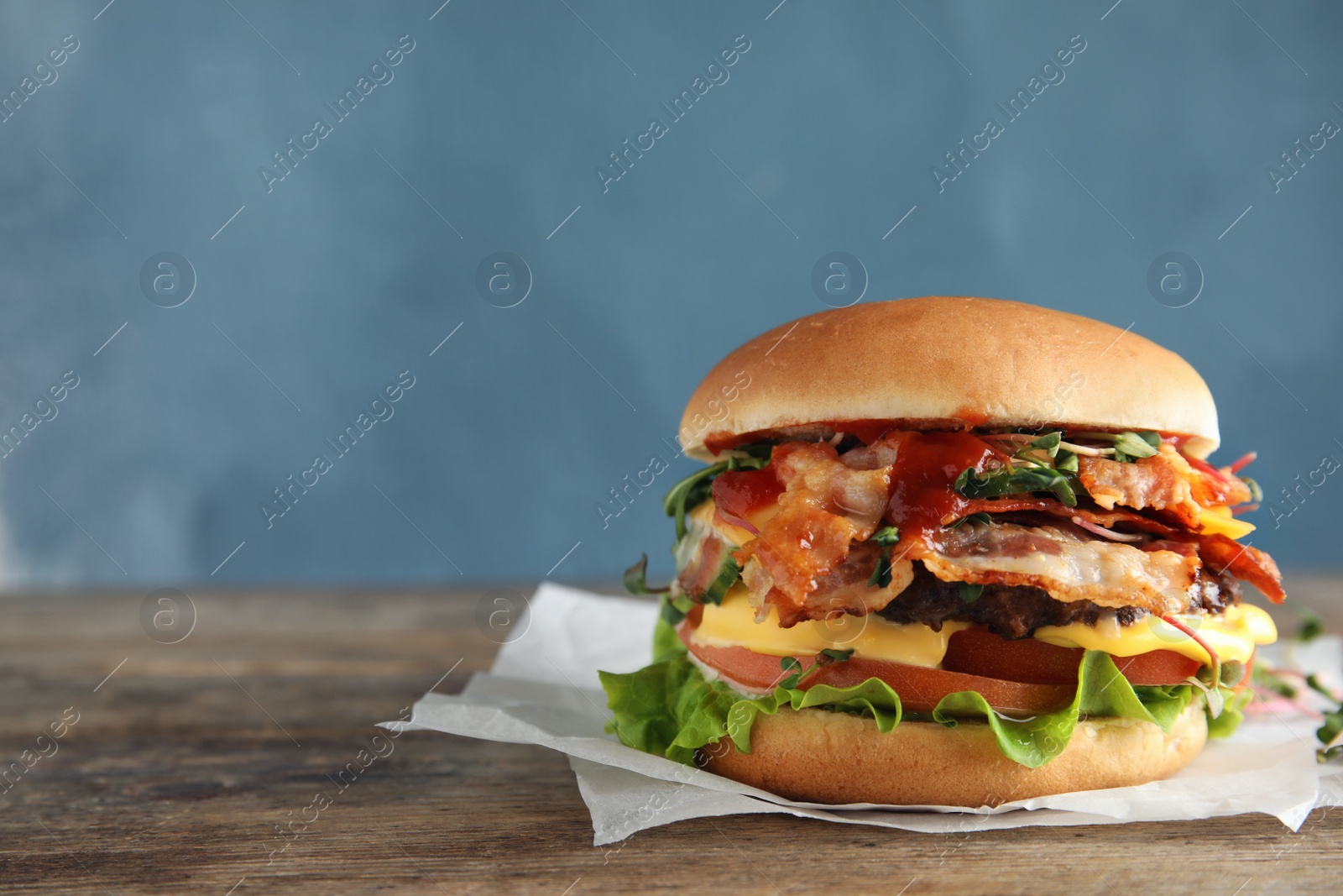 Photo of Tasty burger with bacon on table against color background. Space for text