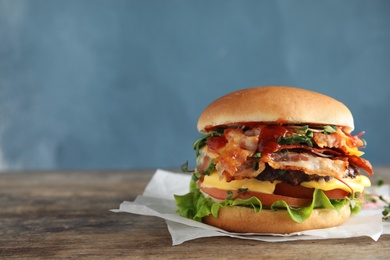 Photo of Tasty burger with bacon on table against color background. Space for text