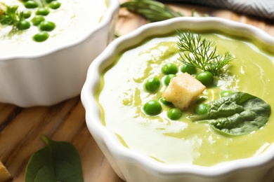 Photo of Fresh vegetable detox soup made of green peas and spinach in dish on table, closeup