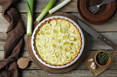Tasty leek pie, knife and products on old wooden table, flat lay
