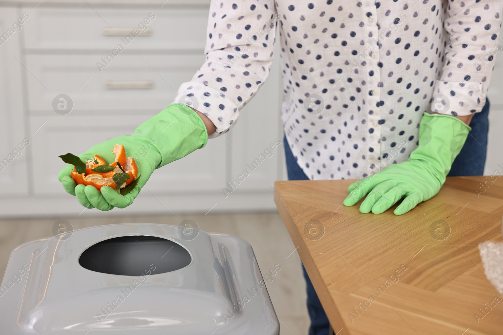 Photo of Woman separating garbage at wooden table indoors, closeup