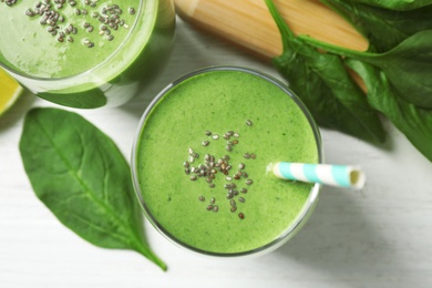 Glasses of healthy green smoothie with fresh spinach on white wooden table, flat lay