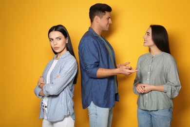 Photo of Unhappy woman feeling jealous while couple spending time together on yellow background