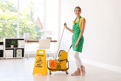 Young woman with mop and bucket cleaning office