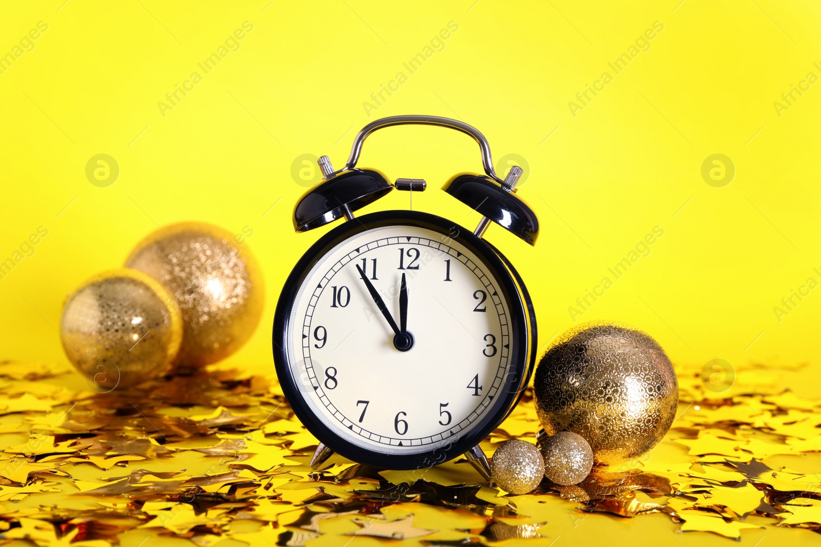 Photo of Vintage alarm clock with Christmas decor on yellow background. New Year countdown